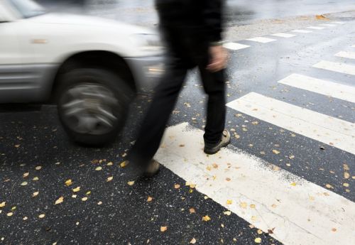 Man on pedestrian crossing in autumn, in danger of being hit by car concept